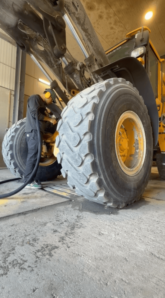 Roue et train de chenilles d'un engin de chantier encrassé de bitume, avant nettoyage cryogénique